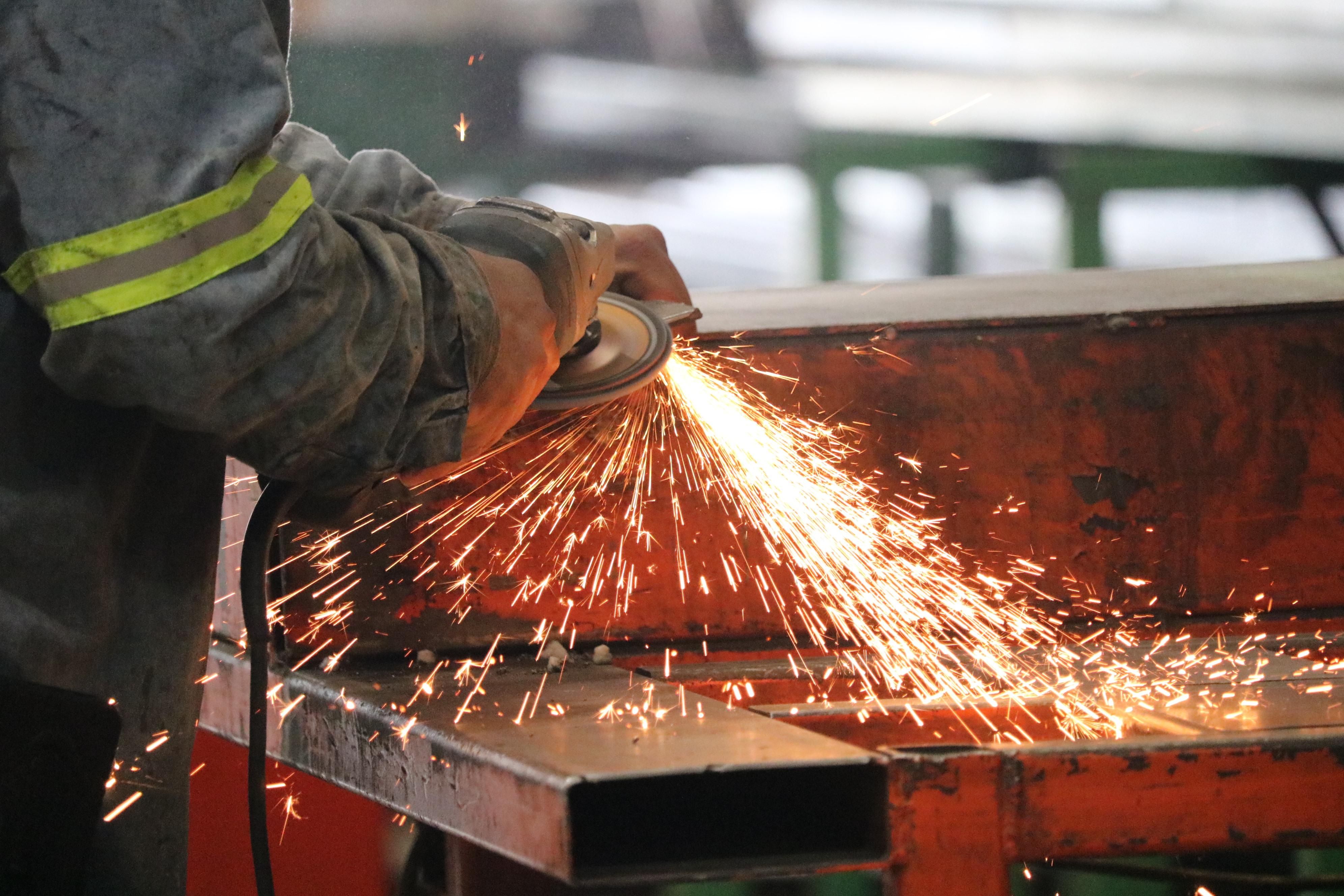 Welder grinding a steel structure with sparks flying